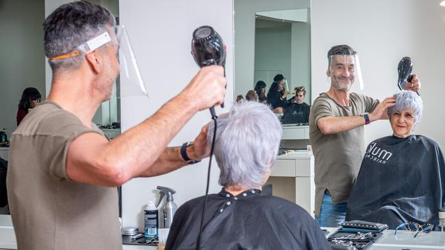 Coburg-based Space Tank Studio has launched a new model of face shield — worn by Cocca Hair Salon owner Don Cocca as he cuts Nella Loft’s hair — it says is about 30 per cent cheaper than equivalent products made in China. Picture: Jake Nowakowski