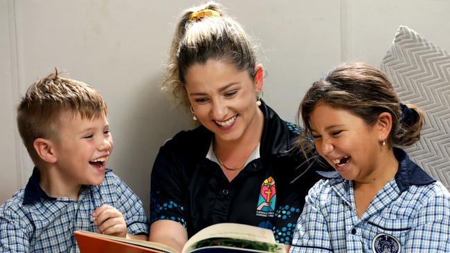 Our Lady Help of Christians Outside School Hours Care co-ordinator Alexis Curtis reads with students Oliver and Poppi Hislop. Photo: Anna Rogers