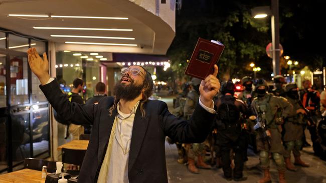 An ultra-Orthodox Jewish man reacts while holding a volume of the Book of Psalms while security forces gather behind at the scene of a shooting attack in Dizengoff Street in the centre of Israel's Mediterranean coastal city of Tel Aviv. Picture: AFP