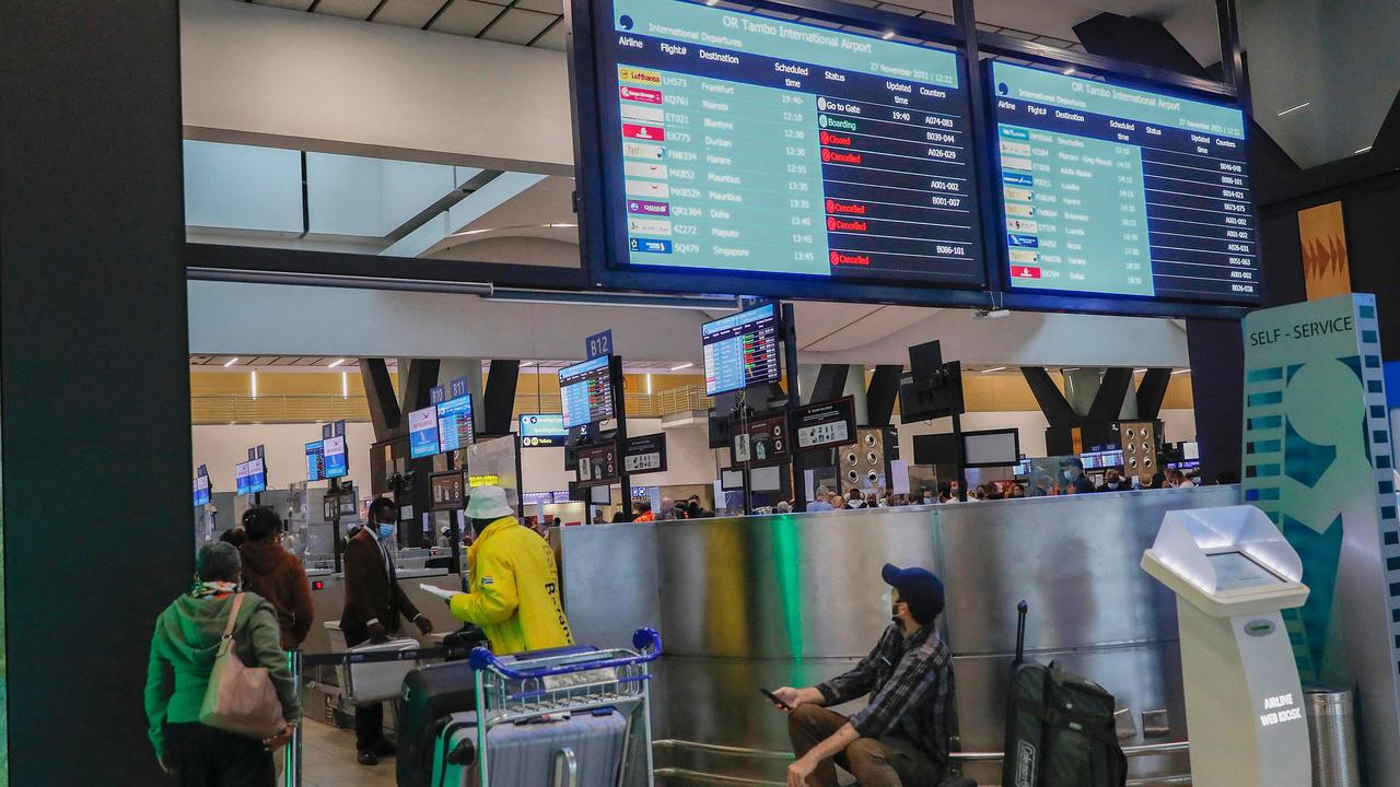 A passenger holds his mobile phone while looking at an electronic flight notice board displaying cancelled flights at OR Tambo International Airport in Johannesburg on November 27, 2021, after several countries banned flights from South Africa following the discovery of a new Covid-19 variant Omicron. Picture: Phill Magakoe / AFP