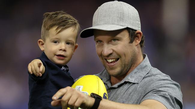 Face of the good Friday Appeal Malu and his dad Morgan wait to present the game ball to the umpires at the North Melbourne v Western Bulldogs clash. Picture: Michael Klein