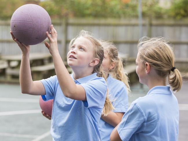 Girls in school uniform playing netball in the school yard