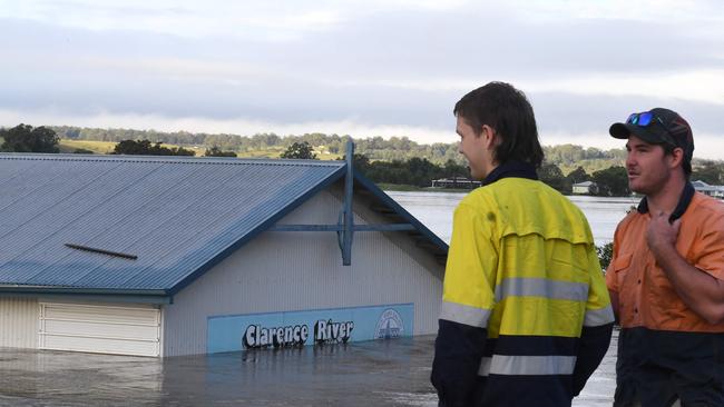 Workers watch a flooded shed at the bank of over flowing Clarence River in Grafton. Photo: SAEED KHAN / AFP