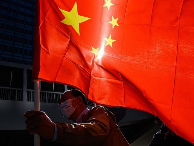 A pro-Beijing supporter holds China's national flag as he and others gather outside the Legislative Council in Hong Kong on November 12, 2020, a day after the city's pro-Beijing authorities ousted four pro-democracy lawmakers. (Photo by Anthony WALLACE / AFP)