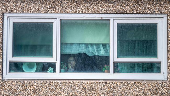 A resident of the Flemington tower in lockdown looks out the window. Picture: Jake Nowakowski