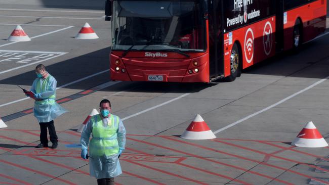 Transport crews and staff in PPE prepare for the first international passenger arrivals at Melbourne Airport. Picture: Andrew Henshaw