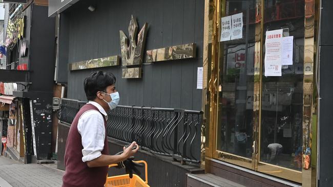 A man wearing a face mask walks past a nightclub, now closed following a visit by a confirmed COVID-19 coronavirus patient, in the popular night-life district of Itaewon in Seoul. Picture: AFP