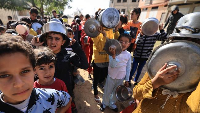 Displaced Palestinian children holding pots and pans wait in line as volunteers distribute a hot meal in Khan Yunis in the southern Gaza Strip on November 23, 2023, as battles between Israel and Hamas militants continue. Picture: Mahmud Hams/AFP