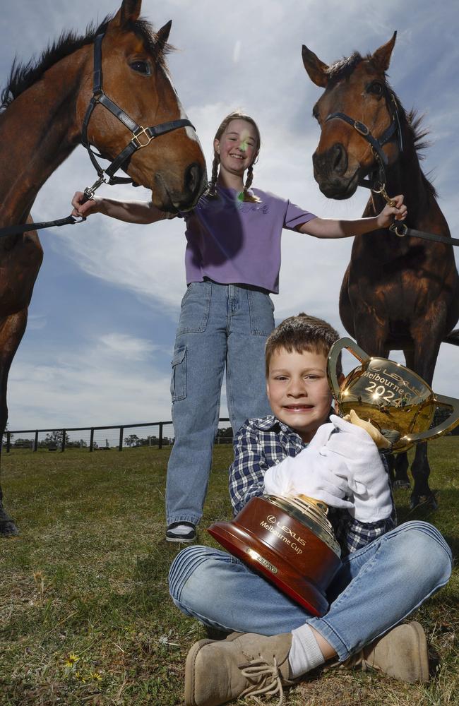 Four-year-old Darcy Favaro holds onto this year’s Melbourne Cup as 12-year-old Isla Shannon holds onto 2015 Melb Cup winner Prince of Penzance (left) and 2016 cup winner Almandin. Picture: Michael Klein