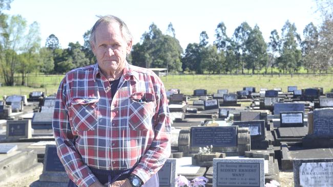 LOW ACT: Trevor Want stands next to the graves of his parents Sidney and Elma and brother Barry at Grafton cemetery. The headstone of four-year-old Barry was smashed by vandals last week.