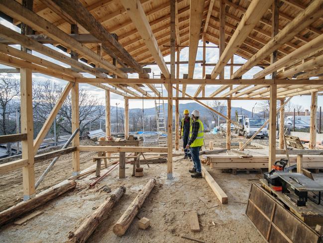 Construction workers in building site of wooden house.