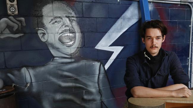 Marcus Christensen with a mural showing British fascist leader Oswald Mosley at his business at Burleigh Heads on the Gold Coast. Picture: Lyndon Mechielsen