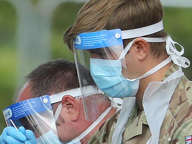 LONDON, UNITED KINGDOM  - MAY 01:  A member of the military  wearing a protective face mask and screen, disposable gloves and a plastic apron, takes a swap at a coronavirus drive-through testing center in the car park of the closed Chessington World of Adventures Resort theme park on May 01, 2020 in London, United Kingdom. British Prime Minister Boris Johnson, who returned to Downing Street this week after recovering from Covid-19, said the country needed to continue its lockdown measures to avoid a second spike in infections. (Photo by Warren Little/Getty Images)