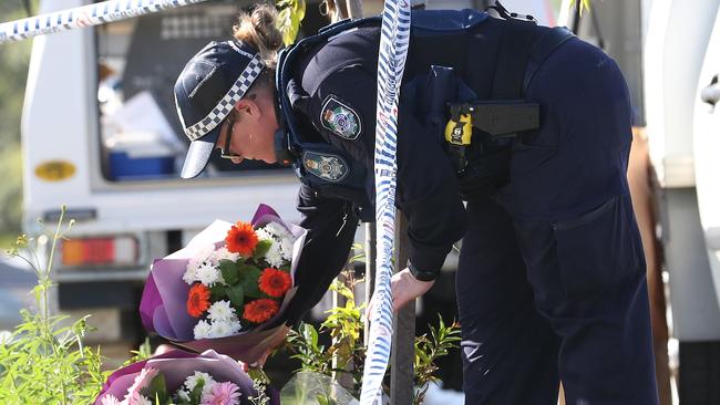 A Police officer places flowers at the scene of a murder-suicide on the Gold Coast.