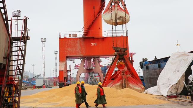 Workers walking past imported soybeans at a port in Nantong in China's eastern Jiangsu province. Picture: AFP