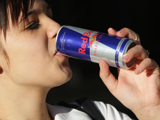 Young woman drinking from a can of Red Bull energy drink in Sydney.