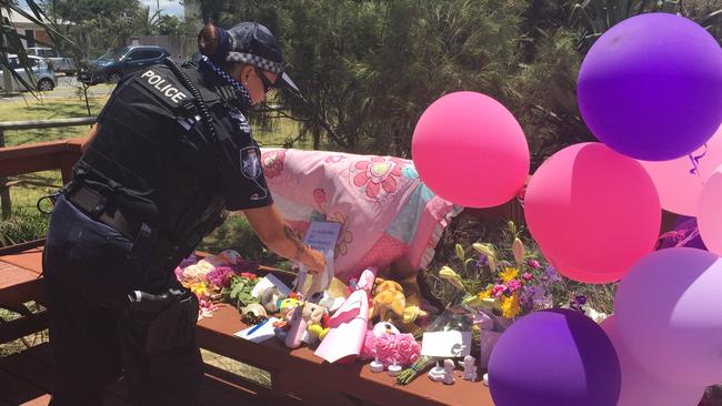 Police officers wipe away tears as they bring toys and pay their respects near where the baby girl was found dead. Picture: Tali Eley.