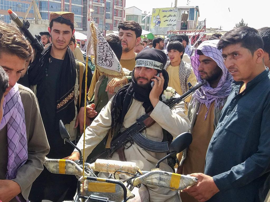 A Taliban fighter (centre) is seen surrounded by locals at Pul-e-Khumri. Picture: AFP