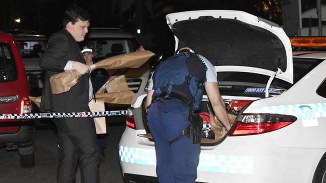 Police are seen taking away evidence bags with long items. Picture: Gordon McComiskie