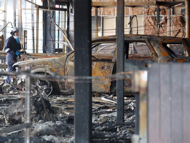 Fire investigators inspect a burnt out car inside the gym. Picture: David Crosling