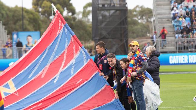 AFL reporter Matt Turner helping Brisbane’s cheer squad hold the banner. Picture: Brett Hartwig