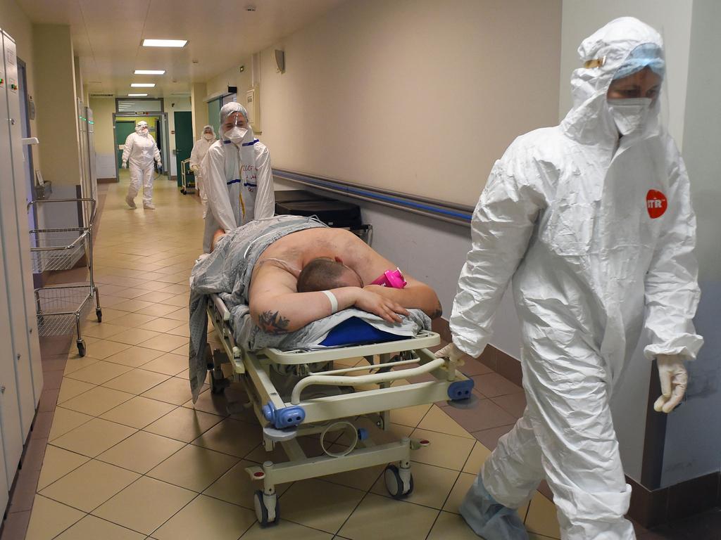 TOPSHOT - Medical workers wearing a personal protective equipment PPE carry a patient infected with the Covid-19 at the intensive care unit of the Mariinsky Hospital in Saint Petersburg on July 7, 2021. - Russia on July 4, 2021 counted more than 25,000 new daily infections after a week of record death tolls as the highly contagious Delta variant propels a global resurgence of the pandemic. The coronavirus has killed nearly four million people worldwide, forcing numerous nations to reimpose restrictions well over a year after the outbreak of the pandemic. (Photo by Olga MALTSEVA / AFP)