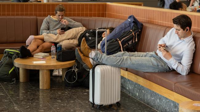 Passengers at Adelaide Airport passing the time on Monday. Picture: Morgan Sette