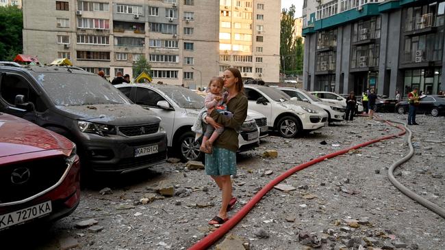 A local resident carries a baby outside a 24-storey building partially destroyed as a result of missiles strike in Ukrainian capital of Kyiv. Picture: AFP