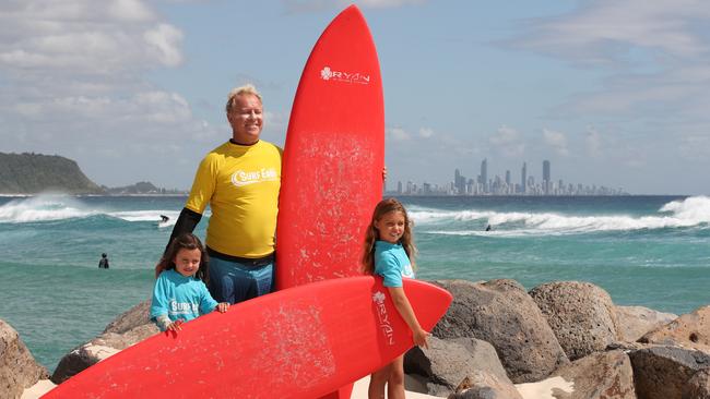 Patrick O’Leary owner of Surf Easy School at Currumbin Alley with students and sisters Evie Thorpe 7 and Aura Thorpe 4. Picture Glenn Hampson