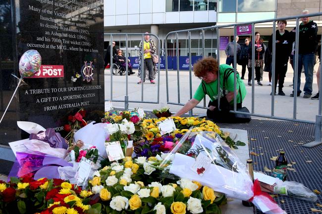 A woman places flowers at the base of a statue of late Australian cricket legend Shane Warne in Melbourne.