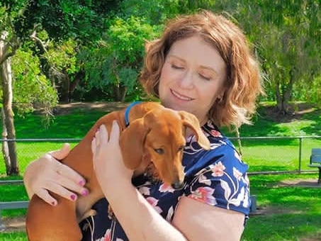 Woman holding dog in a lush green Park, Slade Point, February 2025