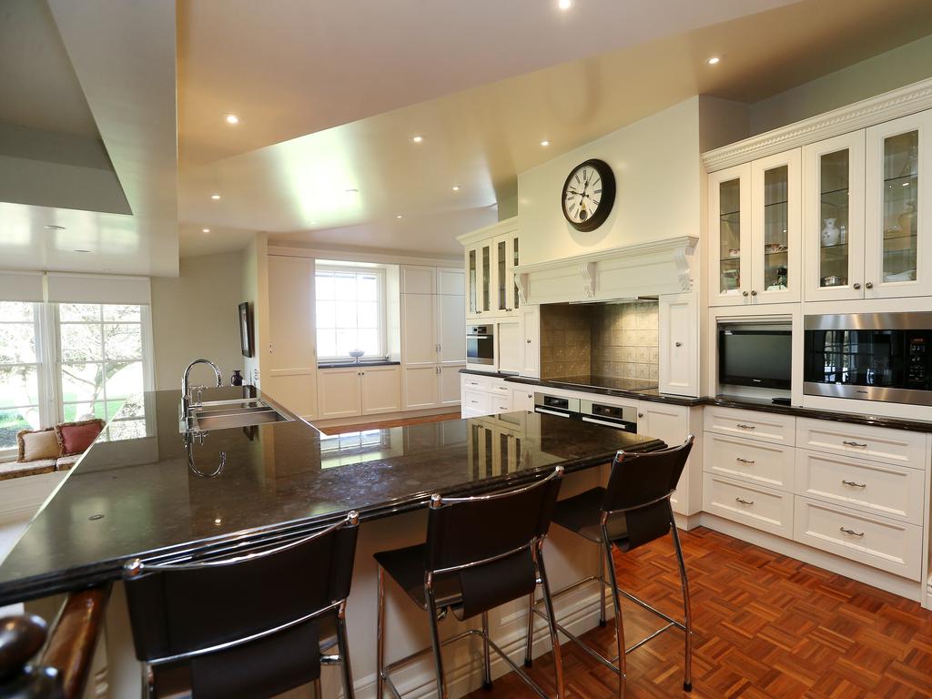 An open-plan kitchen, dining and living zone feature a fireplace and window that frames views of the garden and floods the room with natural light. Picture: Andy Rogers