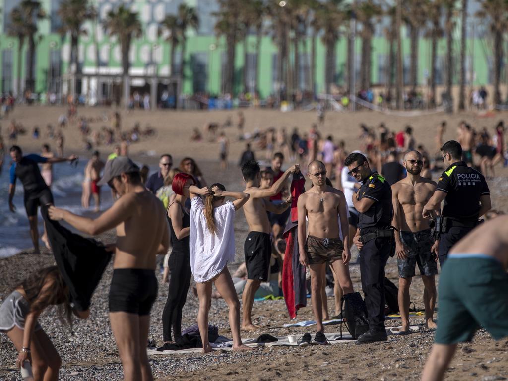 Police officers ask people to not sit while patrolling the beach in Barcelona, Spain, where sunbathing and recreational swimming are still not allowed. Picture: AP Photo