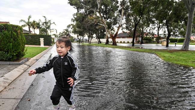 Two-year-old Annie Yang plays in floodwater outside her home in Plympton. Picture: NCA NewsWire / Brenton Edwards