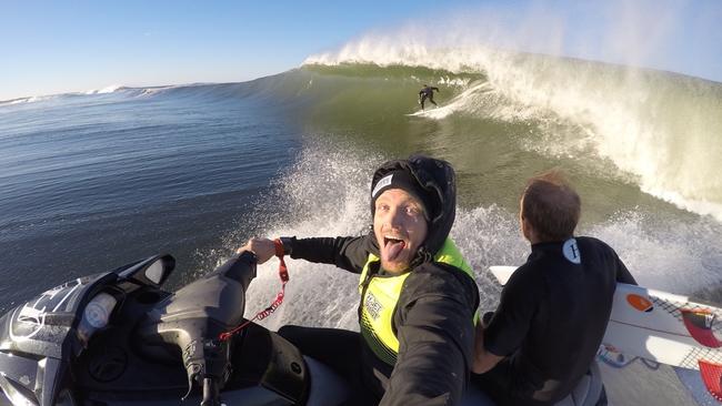 The Mad Hueys co-founder Joel Scott (driving jetski), Josh Dowthwaite on the back of the jetski, and Mad Hueys co-founder Shaun Harrington surfing