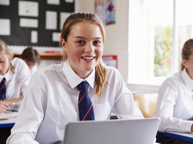 Portrait Of Female Pupil In Uniform Using Laptop In Classroom