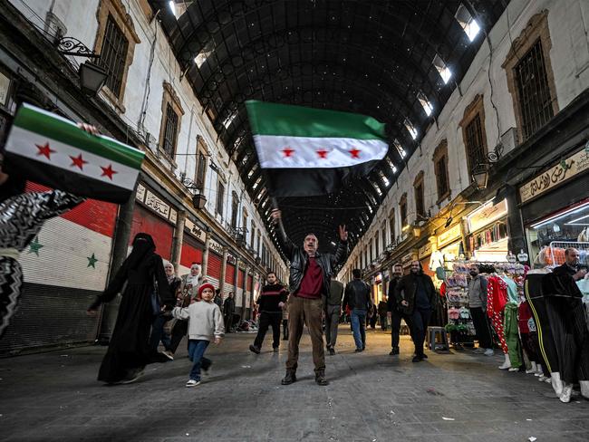 A man reacts as he holds up a Syrian opposition flag along an alley of the Hamidiyah covered market in the old part of Damascus on Tuesday. Picture: AFP