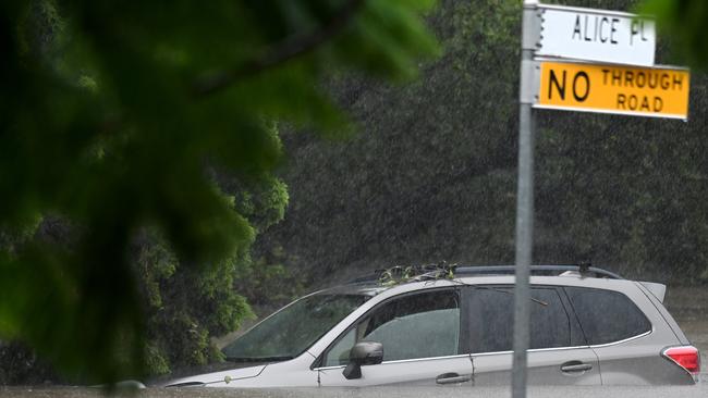 A car goes under as floodwaters rise in Stones Corner. Picture: John Gass