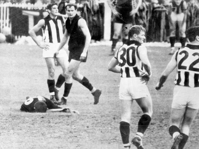 1965. John Somerville on the ground. Somerville's opponent Duncan Wright stands with hands on hips. The men standing are (from left) Duncan Wright (C), Ken Fraser (E), Des Tuddenham and Paul Wadham (C). 1965 Preliminary Final. Collingwood v Essendon.  .The Herald 18/09/1965, page 1Somerville goes down while other players look to where the ball is some distance downfield.  The men standing are (from left) Duncan Wright (C), Ken Fraser (E), Des Tuddenham and Paul Wadham (C).