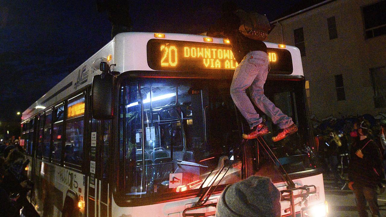 A demonstrator climbs onto a bus in Oakland, California. Picture: Noah Berger/AP