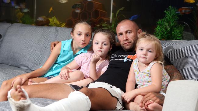 Steve Saillot was in his boat on the Broadwater when it was struck by a jet ski. His leg was broken. Photo of him recovering at his Upper Coomera home with Latisha Saillot, 10, Kloe Randall, 6, and Jade Randall, 3. Photo: Richard Gosling