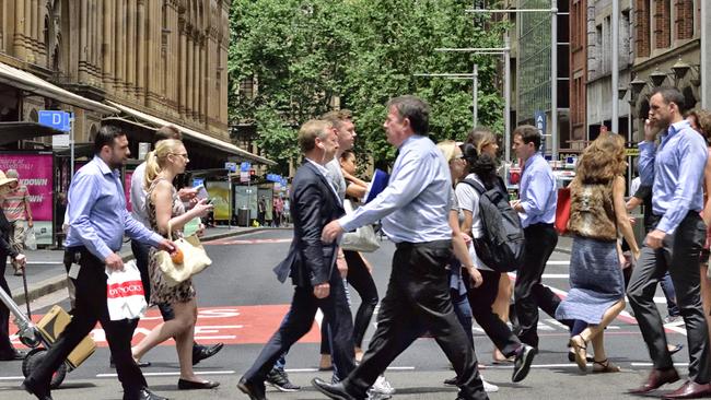 Sydney, Australia - November 12, 2015: People crowd crossing street in central Sydney. Landmark in background, shopping center to the left.