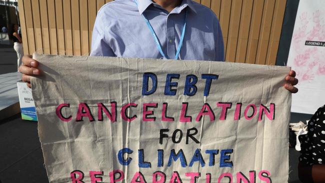 A climate activist holds up a banner demanding the cancellation of developing nations' debts at a demonstration during the COP27 climate conference. Picture: AFP