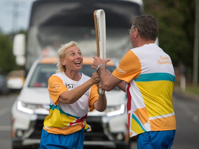 The Queen's Baton, carried by batonbearer Lyn Preston handing over to batonbearer David Ryan, in relay through Mission Beach on Saturday. Pic: SUPPLIED