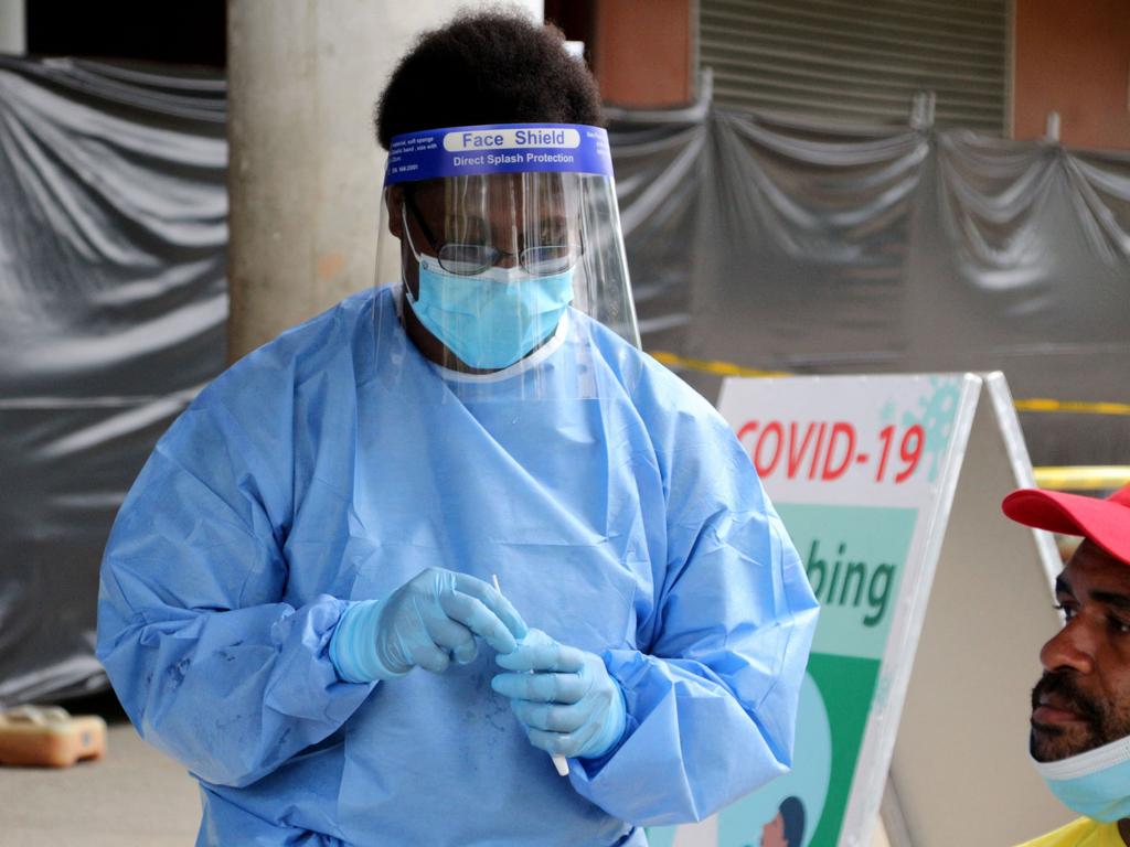 A health worker prepares to take a swab from a man to test for the coronavirus outside a makeshift clinic in a sports stadium in Port Moresby, Papua New Guinea. Picture: AFP