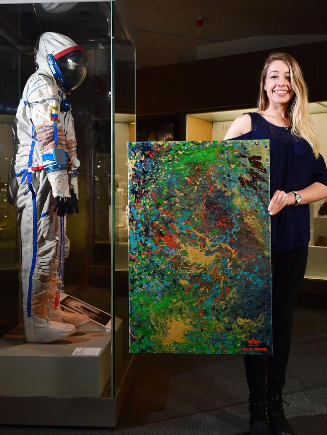 UniSA communication design student Taylor Summers with her artwork <i>Energy Ripples Space: Our Eye on the Sky</i>, which is part of an exhibition at SA Museum timed to coincide with the International Astronautical Congress. Picture: AAP/Keryn Stevens