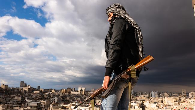 A man with a Kalashnikov rifle looks across the city of Homs on Monday. Picture: Spencer Platt/Getty Images