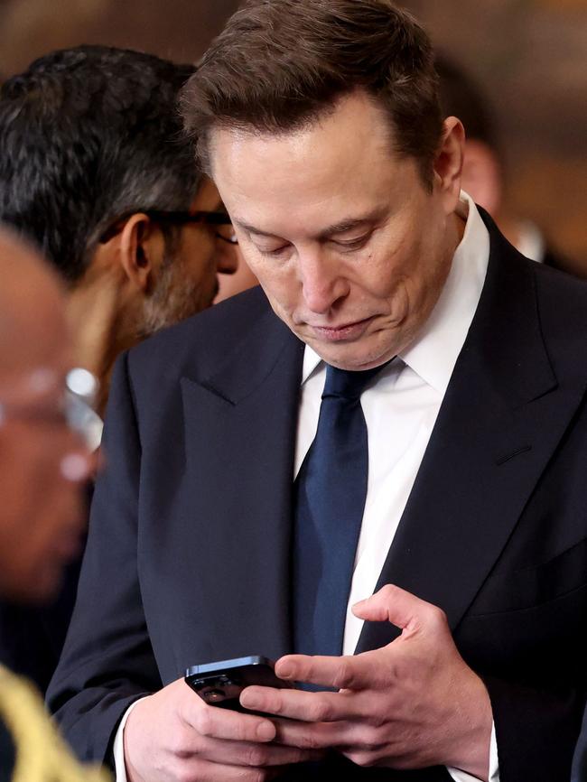 Elon Musk checks his phone at the ceremony. He has not commented on the lawsuit. Picture: AFP