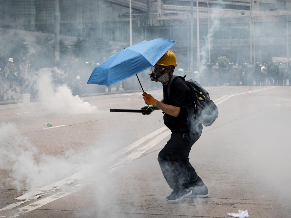 A pro-democracy protester runs through tear gas during clashes with police after a march in Hong Kong. Picture: Getty