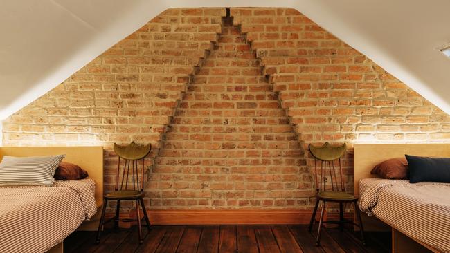 Little Brick Cottage’s attic bedroom, which includes original features such as handmade bricks and wide floorboards, is relatively unchanged since it was first built. Picture: Adam Gibson